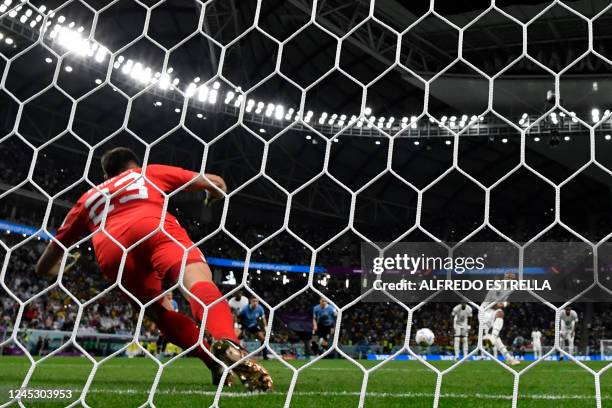 Uruguay's goalkeeper Sergio Rochet dives to save a penalty shot by Ghana's midfielder Andre Ayew during the Qatar 2022 World Cup Group H football...