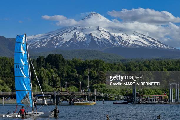 Tourists are seen on a beach near the Villarrica volcano in Pucon, Chile, on December 2, 2022. - Villarrica volcano is on yellow alert due to its...