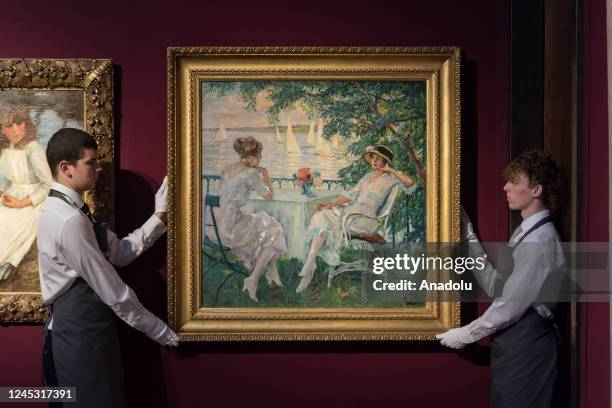 Art handlers hold a painting titled 'Les yachts' by Edward Alfred Cucuel estimate Â£100,000-150,000 during a photo call for the upcoming Classic Week...