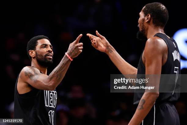 Kyrie Irving of the Brooklyn Nets reacts with teammate Kevin Durant against the Toronto Raptors during the second half at Barclays Center on December...