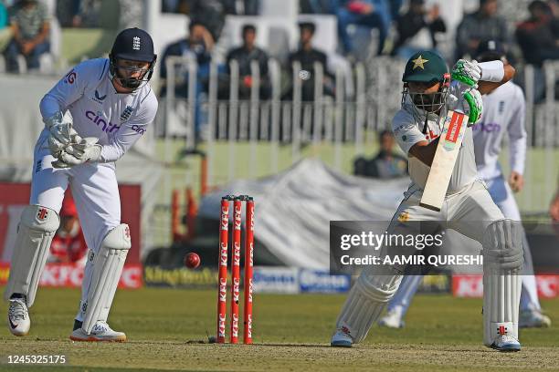 Pakistan's captain Babar Azam plays a shot as England's wicketkeeper Ollie Pope watches during the third day of the first cricket Test match between...