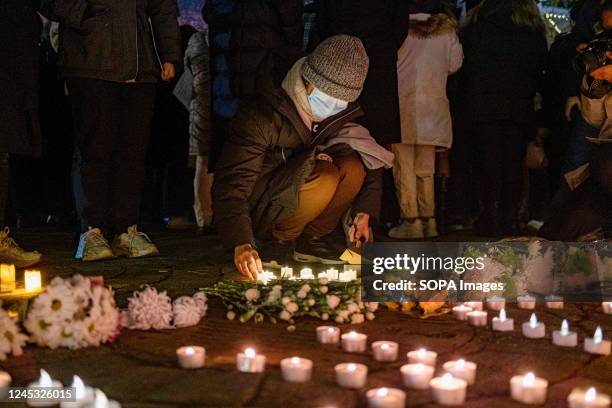 Demonstrator places a lit candle on the ground during a candlelight vigil for the Urumqi tragic fire victims at Tiananmen Memorial. Over 400 people...