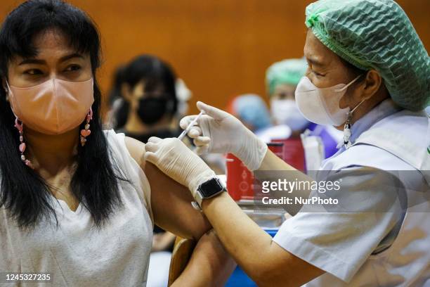People receive doses of the Pfizer COVID-19 vaccine booster at a vaccination center inside a stadium in Bangkok, Thailand, 03 December 2022. Health...