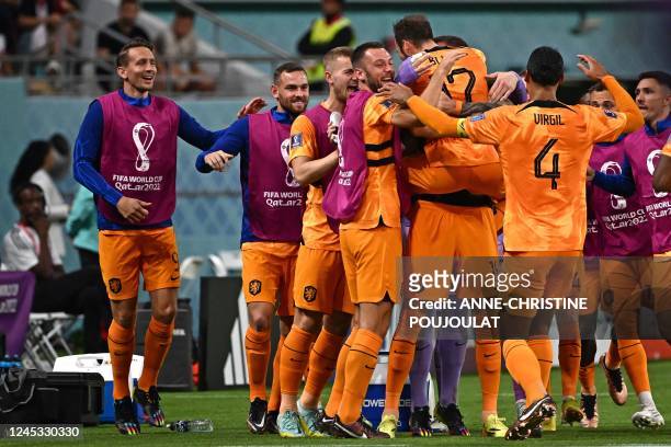 Netherlands' defender Daley Blind celebrates with teammates after he scored his team's second goal during the Qatar 2022 World Cup round of 16...