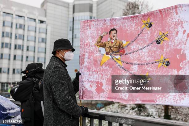 Demonstrators hold a banner depicting Chinese President Xi Jinping in Nazi uniform during a protest in front of the Chinese Embassy in solidarity...