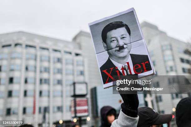 Demonstrator holds a banner with an image of Chinese President Xi Jinping with a "Hitler moustache", during a protest in front of the Chinese Embassy...