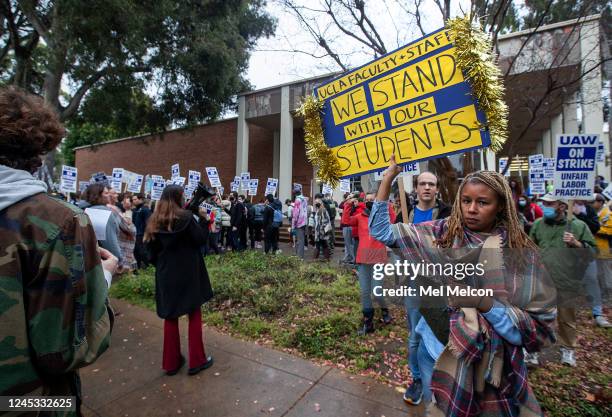 Latoya Baldwin, right, an assistant professor at the UCLA school of law, holds up a sign in support of graduate student workers, on strike, calling...