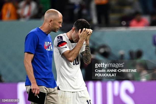 S forward Christian Pulisic reacts next to USA's coach Gregg Berhalter after his team lost the Qatar 2022 World Cup round of 16 football match...
