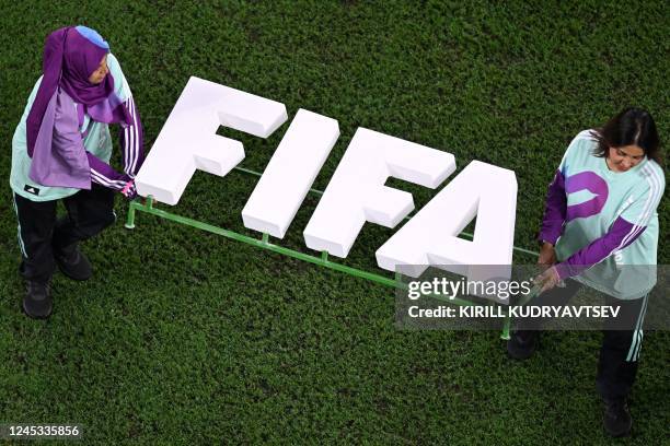 Volonteers carry a FIFA logo ahead of the Qatar 2022 World Cup round of 16 football match between Argentina and Australia at the Ahmad Bin Ali...