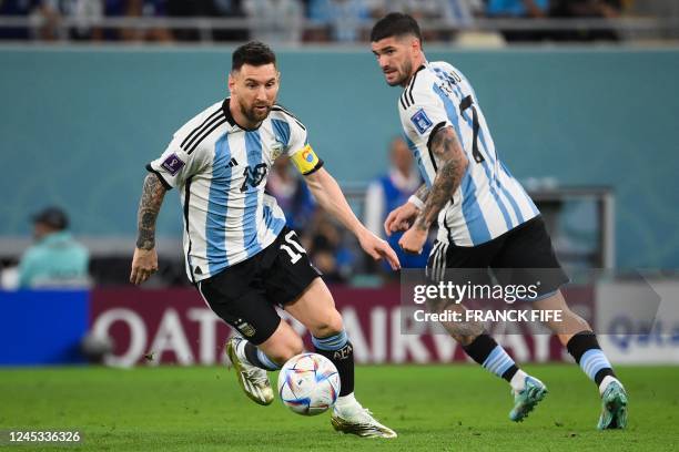 Argentina's forward Lionel Messi runs with the ball next to Argentina's midfielder Rodrigo De Paul during the Qatar 2022 World Cup round of 16...