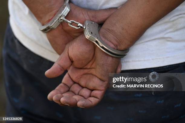 Man remains handcuffed after being detained by the police during an operation against gang members in Soyapango, El Salvador, on December 3, 2022. -...