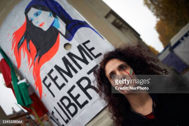 Woman stands near a drawing depicting Mahsa Amini reading 'women, life, freedom'. Iranians of Toulouse organized a protest in Toulouse in solidarity...