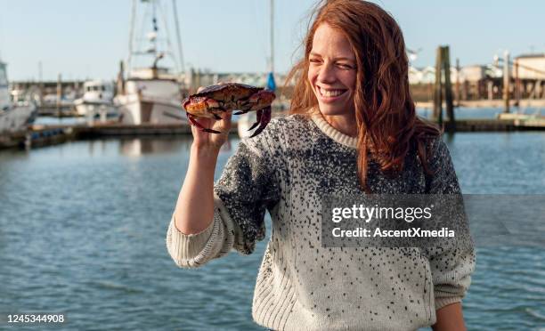 young woman smiles as she holds up crab she caught - crabbing stock pictures, royalty-free photos & images