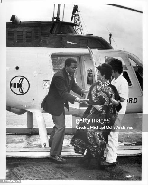 Sidney Poitier helping Esther Anderson out of a helicopter in a scene from the film 'A Warm December', 1973.