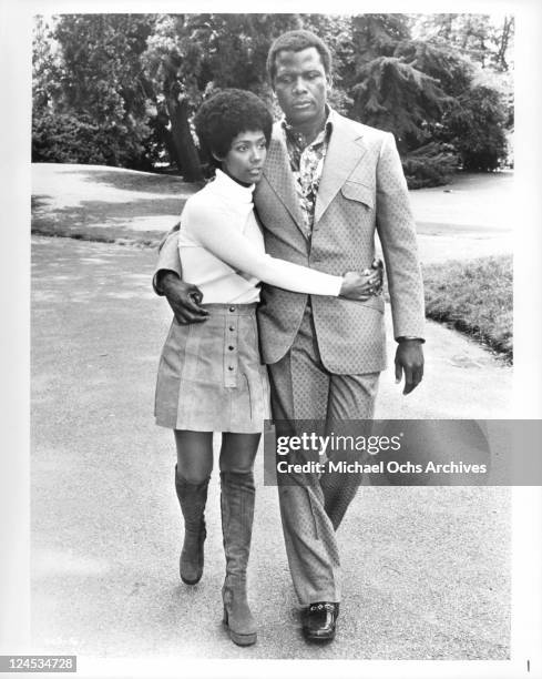 Esther Anderson and Sidney Poitier walking arm in arm in a scene from the film 'A Warm December', 1973.