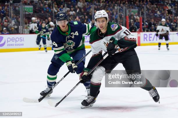 Ethan Bear of the Vancouver Canucks defends against Dylan Guenther of the Arizona Coyotes during the second period of their NHL game at Rogers Arena...