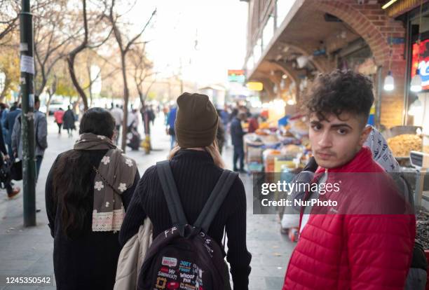 Iranian youths walk along a street-side near Tehran Grand Bazaar , December 3, 2022.