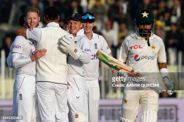 England's Ben Stokes celebrates with teammate after taking the wicket of Pakistan's Babar Azam during the fourth day of the first cricket Test match...