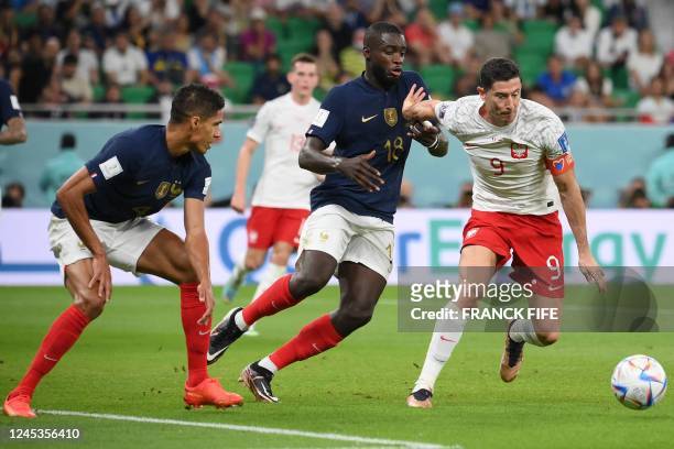 Poland's forward Robert Lewandowski fights for the ball with France's defender Dayot Upamecano and France's defender Raphael Varane during the Qatar...