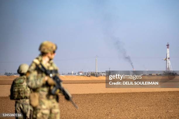 Soldiers look towards a flare stack at a local oil field as they patrol the countryside of Rumaylan in Syria's northeastern Hasakeh province near the...