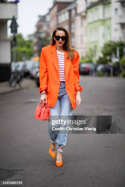 Alexandra Lapp is seen wearing an orange oversized-blazer from The Attico, striped T-shirt with shoulder pads from Mango, Levis 501 Jeans in light...