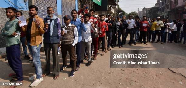 Voters seen standing in queues to cast their vote inside a Polling booth made in a Government School for the MCD elections 2022, on December 4, 2022...