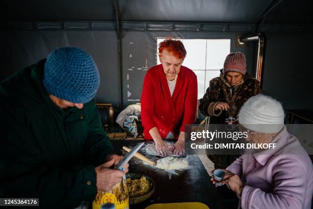 Local residents, living in a modular town after their houses have been destroyed, cook in a tent where they can warm up in Borodyanka, near Kyiv on...