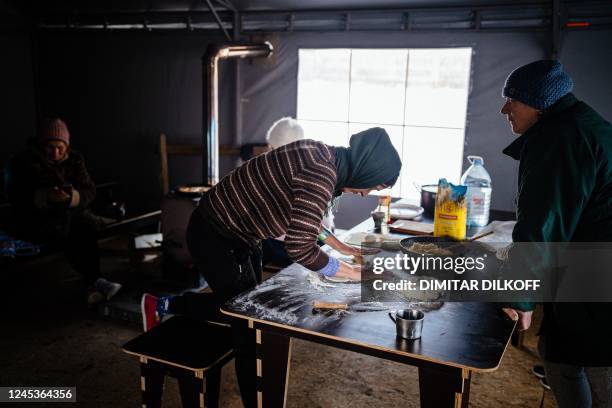 Local residents, living in a modular town after their houses have been destroyed, cook in a tent where they can warm up in Borodyanka, near Kyiv on...