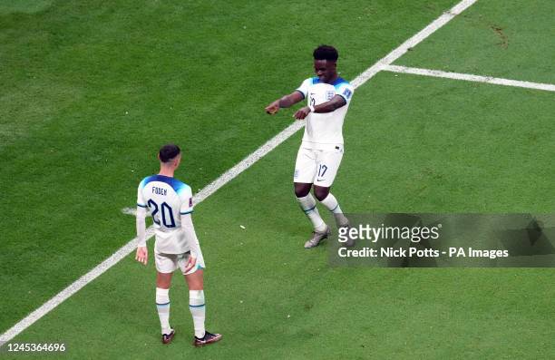 England's Bukayo Saka celebrates scoring the third goal with Phil Foden during the FIFA World Cup Round of Sixteen match at the Al-Bayt Stadium in Al...
