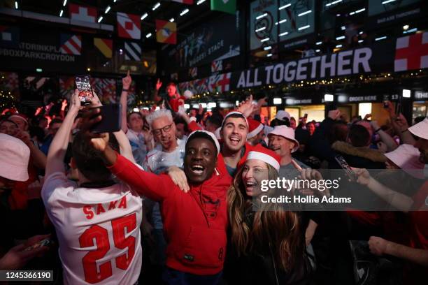 England fans cheer as they celebrate England's victory in their Round of 16 FIFA World Cup match against Senegal at BOXPARK Croydon on December 4,...