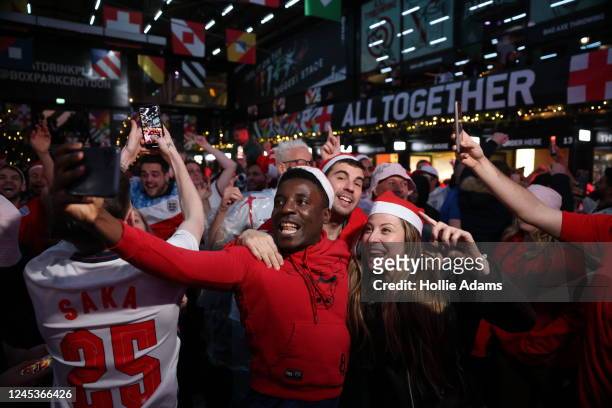 England fans cheer as they celebrate England's victory in their Round of 16 FIFA World Cup match against Senegal at BOXPARK Croydon on December 4,...