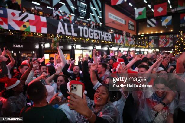 England fans cheer as they celebrate England's victory in their Round of 16 FIFA World Cup match against Senegal at BOXPARK Croydon on December 4,...