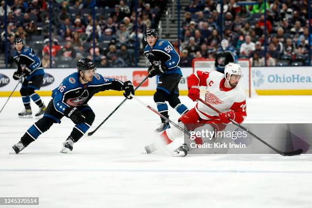 Jack Roslovic of the Columbus Blue Jackets trips Dylan Larkin of the Detroit Red Wings while chasing after the puck during the second period of the...