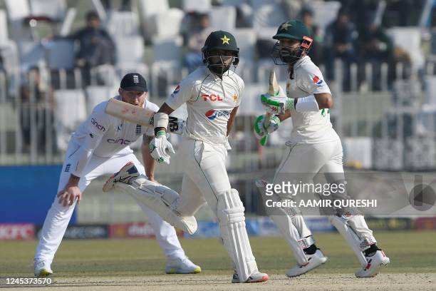 Pakistan's Saud Shakeel and teammate Mohammad Rizwan run between wickets as England's captain Ben Stokes watches during the fifth and final day of...