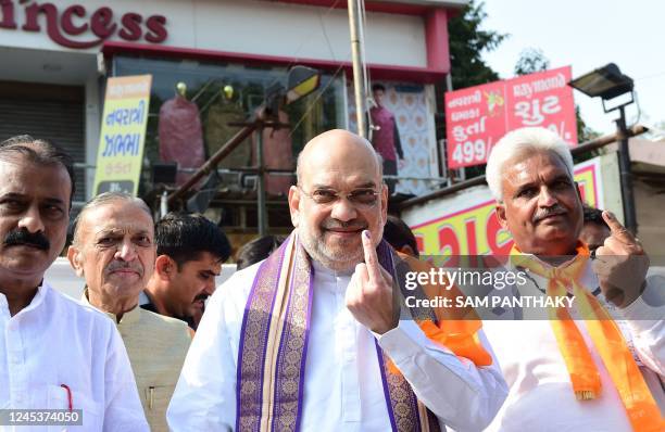 Indian Home Minister Amit Shah shows his ink-clad finger after casting his vote for the second phase of the Gujarat state assembly election in...