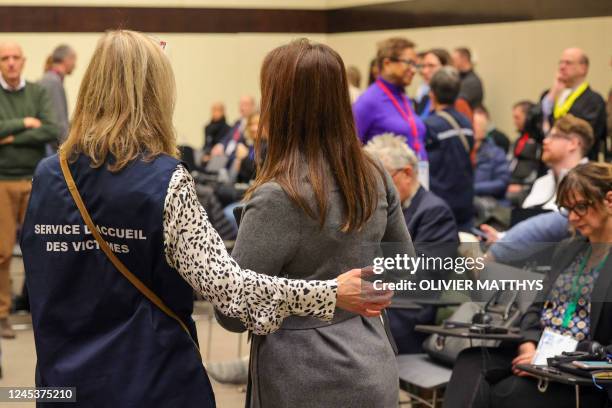 An aide escorts a victim to her seat in the courtroom before the start of the trial of alleged jihadists accused of directing or aiding suicide...