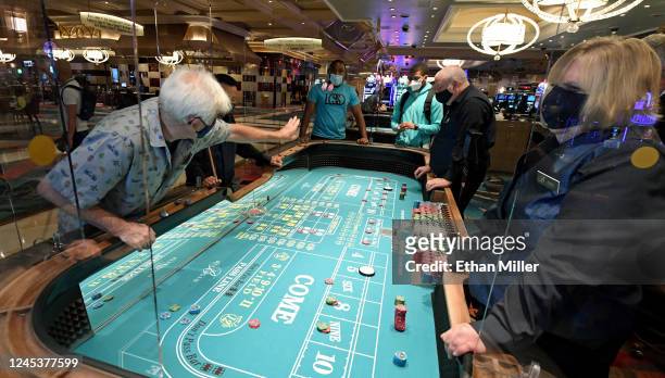 Guests play craps on a table with plexiglass safety shields at Bellagio Resort & Casino on the Las Vegas Strip after the property opened for the...