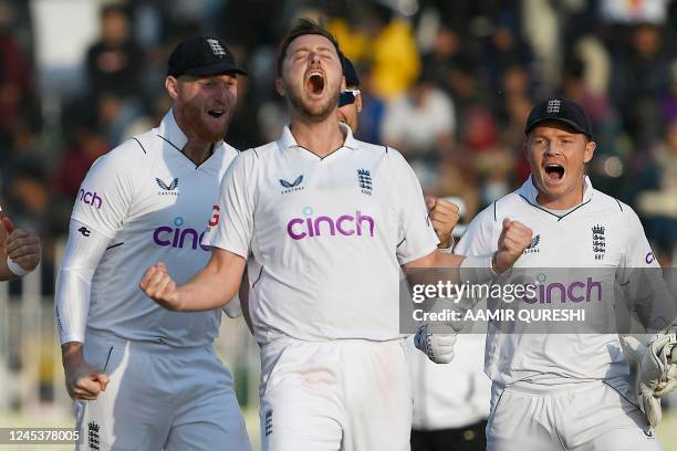 England's Ollie Robinson celebrates teammate after taking the wicket of Pakistan's Salman Ali Agha during the fifth and final day of the first...