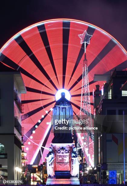 December 2022, Baden-Wuerttemberg, Karlsruhe: A Ferris wheel on Karlsruhe's market square makes its rounds as part of the Christmas market . In the...