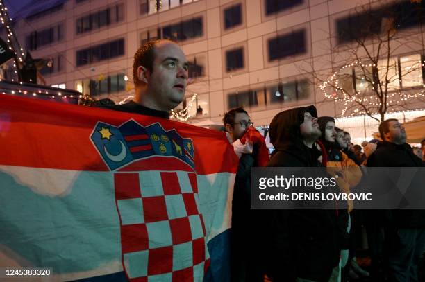 Croatian supporter holds the flag of Croatia as he watches a televised broadcast of the Qatar 2022 World Cup round of 16 football match between Japan...