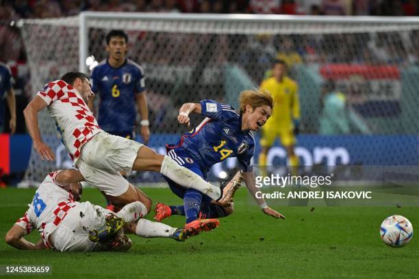 Croatia's defender Borna Barisic tackles Japan's midfielder Junya Ito during the Qatar 2022 World Cup round of 16 football match between Japan and...