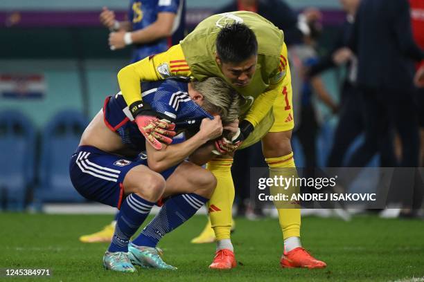 Japan's forward Takuma Asano is consoled by Japan's goalkeeper Eiji Kawashima after they lost the Qatar 2022 World Cup round of 16 football match...