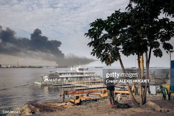 Residents observe smoke billowing from a fire raging near the city of Brazzaville, the capital of the Republic of Congo, as seen from Kinshasa, the...