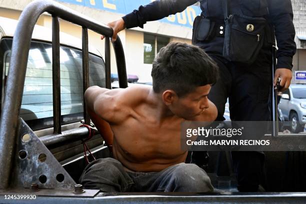 An arrested gang member is held on a police vehicle in Soyapango, El Salvador, on December 5, 2022. - The huge security operation of around 10,000...