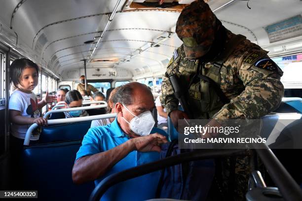 Soldier checks the belongings of a passenger inside a bus during an operation against gang members, in Soyapango, El Salvador, on December 5, 2022. -...