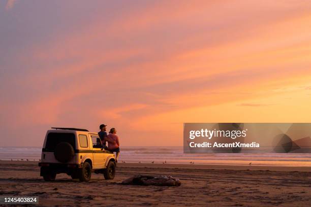 paar steigen aus dem auto, um sonnenaufgang zu beobachten - zwielicht stock-fotos und bilder