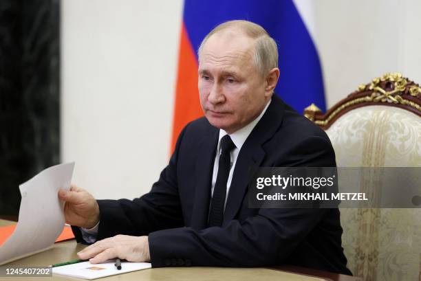 Russia's President Vladimir Putin chairs a meeting with members of the Security Council via a video conference call at the Novo-Ogaryovo state...