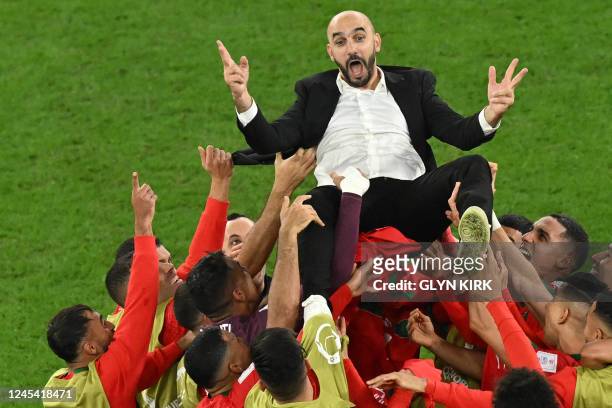 Morocco's players throw Morocco's coach Walid Regragui in the air as they celebrate at the end of the Qatar 2022 World Cup round of 16 football match...
