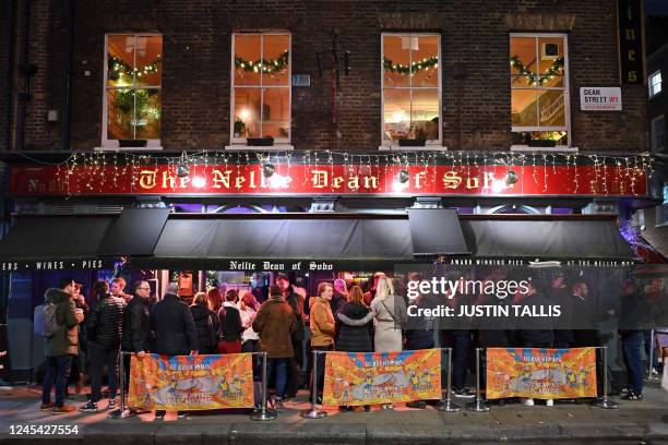 Customers stand drinking outside the Nellie Dean of Soho pub in central London on December 1, 2022. After two years of pandemic and ruined...