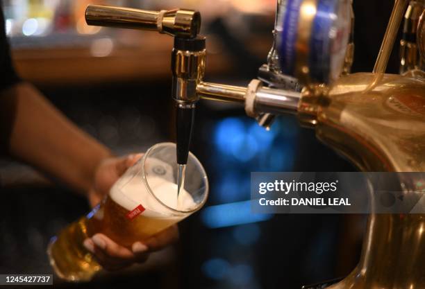 An employee pours a pint of Peroni beer on at the bar in the Mad Hatter pub and hotel, operated by Fuller's, in London on November 30, 2022. At The...